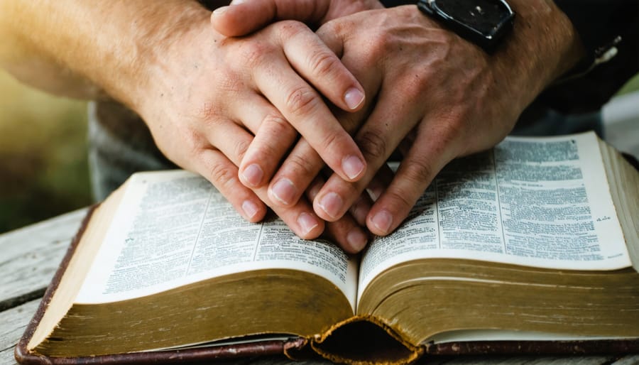 Peaceful scene of praying hands resting on an open Bible with morning light streaming in