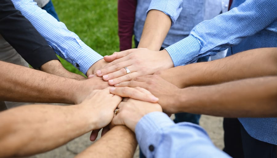 Diverse group of hands joined in prayer during campus meeting